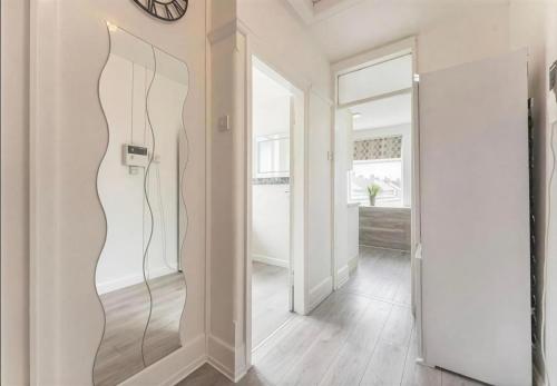 a hallway with a door with a clock on the wall at Walsgrave Road 3BR Multi-Floor Apartment Unit - Free Parking & WiFi in Wyken