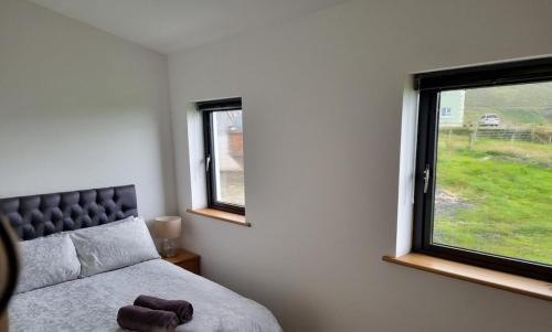 a bedroom with a bed and two windows at Silver Strand Chalets - Chalet 2 in Malin Beg