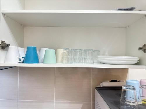 a kitchen shelf with cups and glasses on it at Voila PD Homestay in Lukut