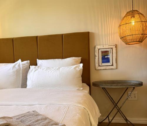 a bedroom with a bed with white pillows and a lamp at Mimosa Cottage in Cape Town