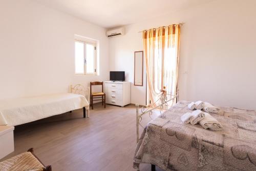 a bedroom with two beds and a dresser and a window at Agriturismo Azzarone in Vieste