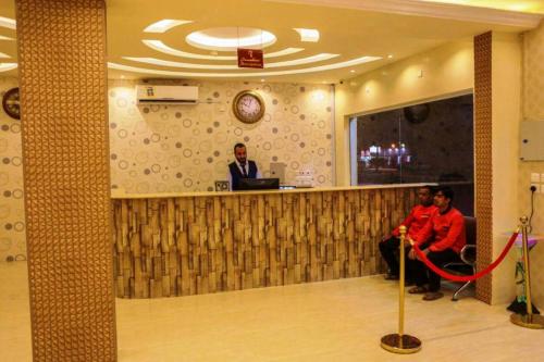 two people sitting at a bar with a man standing at a counter at اجواء المساء للشقق المخدومة in Wadi Al Dawasir