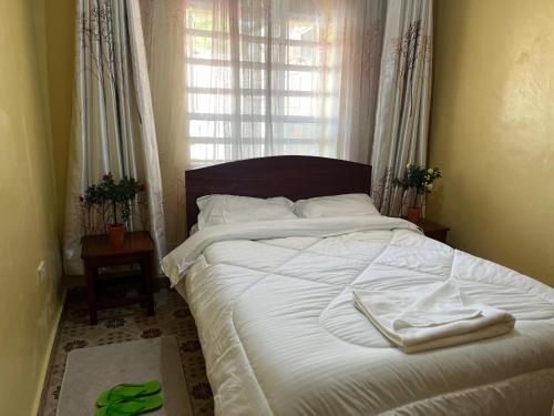 a bedroom with a bed with white sheets and a window at Golf BnB in Nyahururu