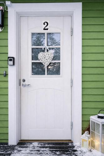 a white door with the number on it on a green house at Lumi & Luonto - Entire 100 sqm 3-BR house with private wood fired sauna in Oulu