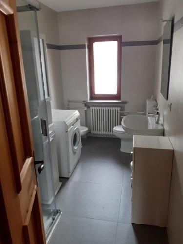 a bathroom with a sink and a toilet and a window at Casa Milpa in Sappada