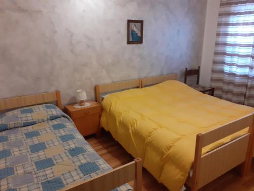 two beds in a small room with yellow sheets at Casa Milpa in Sappada