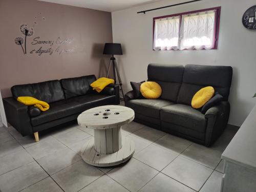 a living room with two couches and a table at Le gîte des hallais in Bouelles