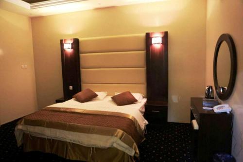 a hotel room with a bed and a mirror at اجواء المساء للشقق المخدومة in Wadi Al Dawasir