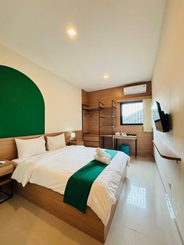 a bedroom with a large bed with a green wall at Saptama Living in Citaringgul 1