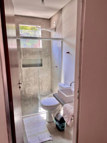 a bathroom with a toilet and a glass shower at Shiva Hostel in Rio das Ostras