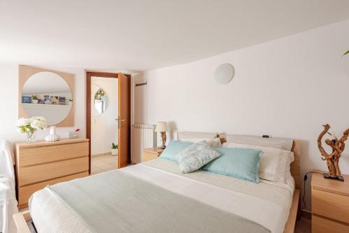 a white bedroom with a large bed with blue pillows at Lovely Flat with See View in Roseto degli Abruzzi