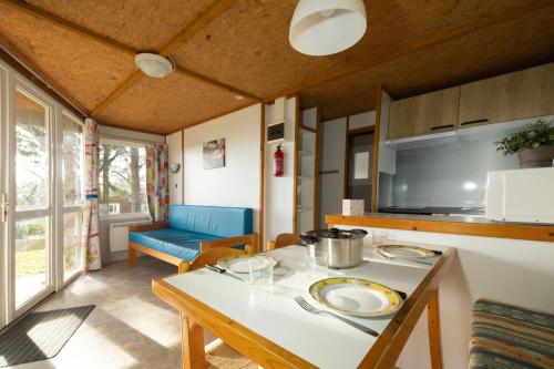 a kitchen and living room with a table and a couch at Camping Domaine Papillon in Reyrevignes
