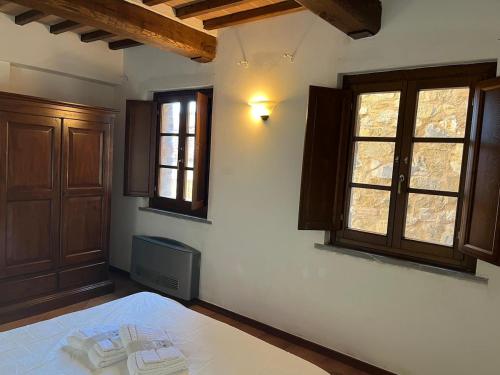 a bedroom with a bed and two windows at Chianti Borgo 28 in Gaiole in Chianti