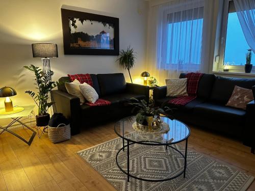 a living room with two couches and a glass table at Gerecse View Apartman in Dunaszentmiklós