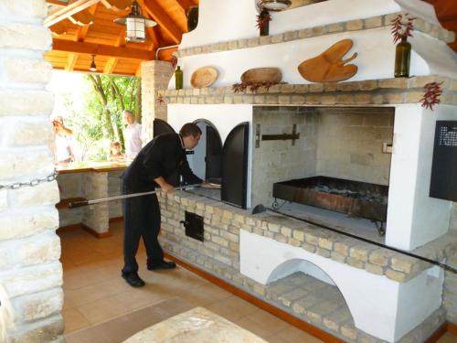 a man preparing food in a brick oven at Geréby Kúria Hotel és Lovasudvar in Lajosmizse