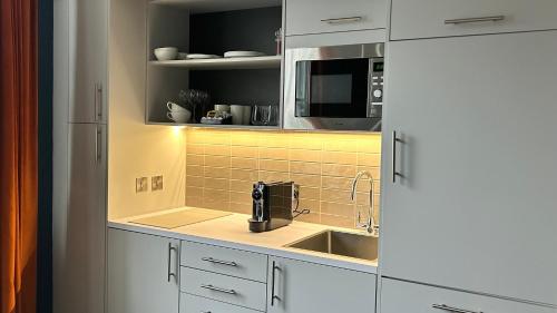 a kitchen with a sink and a microwave at Heeton Concept Aparthotel Edinburgh Queen Street in Edinburgh