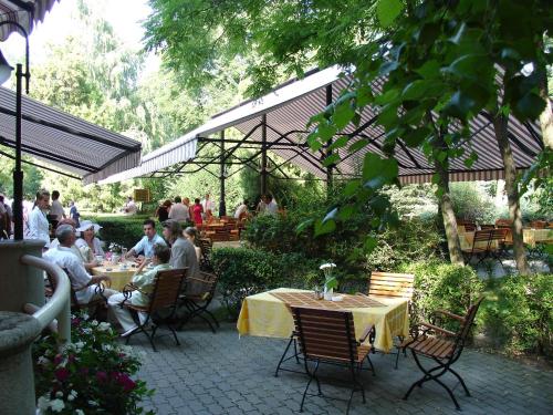 a group of people sitting at tables in a garden at Geréby Kúria Hotel és Lovasudvar in Lajosmizse