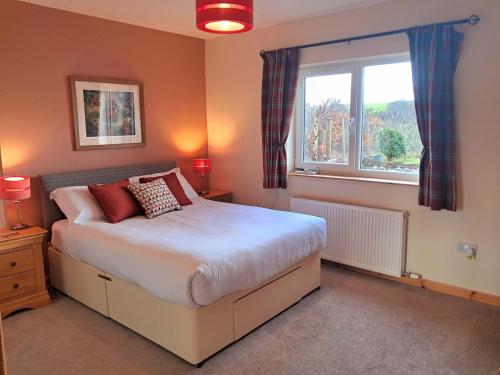 a bedroom with a large bed and a window at Roe Deer Cottage in Beauly