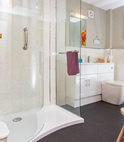 a white bathroom with a shower and a toilet at Roe Deer Cottage in Beauly