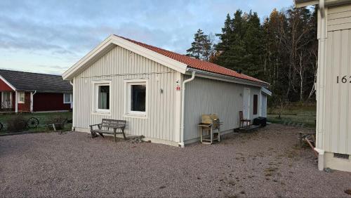 a small white shed with a bench in a yard at Lillstugan i Rasbo in Uppsala