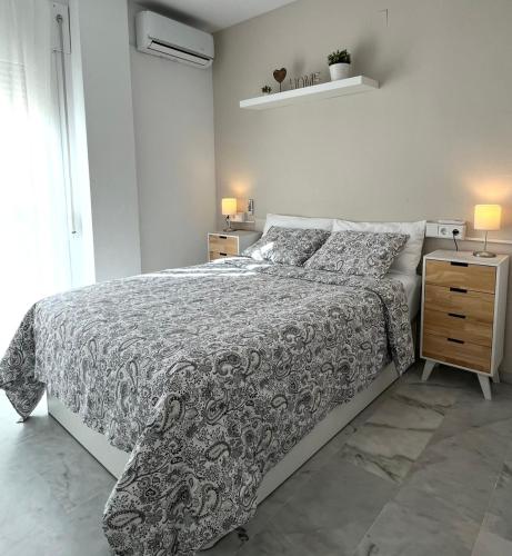 a white bedroom with a bed and a night stand at Beach Side Heaven in Fuengirola