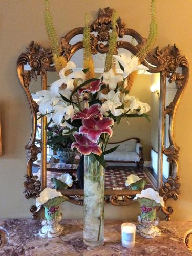 a vase of flowers on a table in front of a mirror at Castle Grove Country House Hotel in Letterkenny