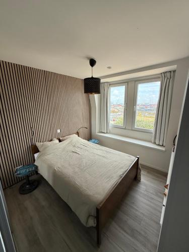 a bedroom with a large bed and two windows at Residentie Palace Zeebrugge 404 in Zeebrugge