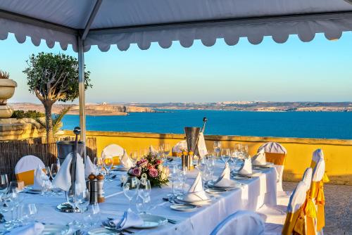 a dining room table with chairs and umbrellas at Grand Hotel Gozo in Għajnsielem