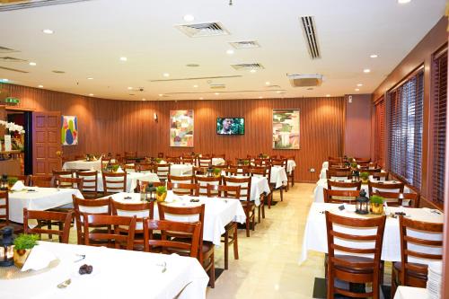 a restaurant with white tables and wooden walls at Grand Central Hotel in Dubai