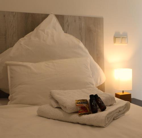 a white bed with a white pillow and towels at DUTTI'S HOME - 1 Zimmer Apartment, Küche, Self-Check-in, Stellplatz in Ingolstadt