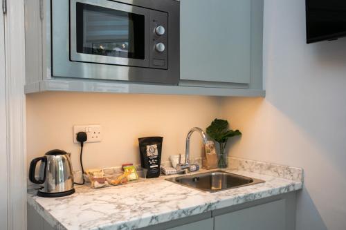 a kitchen counter with a sink and a microwave at Staycoastal Linden Hotel Family Deluxe Suite in Whitley Bay