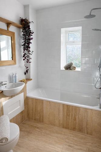 a bathroom with a tub and a toilet and a sink at Fernhill Hideaway in Charmouth