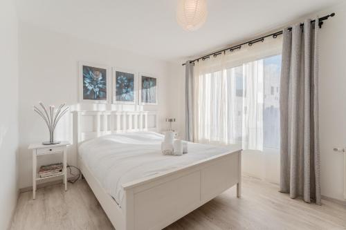 a white bedroom with a white bed and a window at Dumbo - Île de Nantes in Nantes
