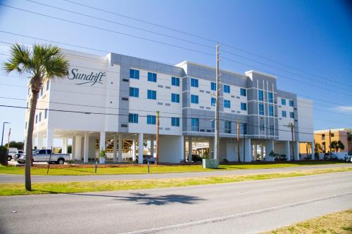 a large white building with a palm tree in front of it at Sundrift Inn in Fort Walton Beach