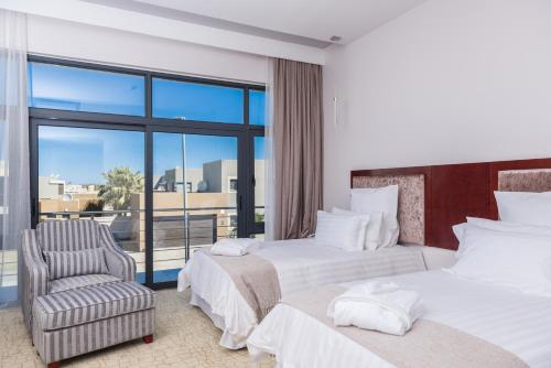 a hotel room with two beds and a chair at Flamingo Villas Boutique Hotel in Walvis Bay