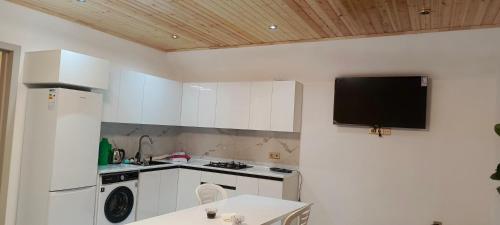 a kitchen with white cabinets and a tv on the wall at Shahdag A-Frame in Qusar