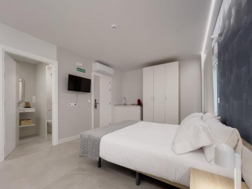 a white bedroom with a bed and a television at 6 de Mayo alojamientos in Almansa