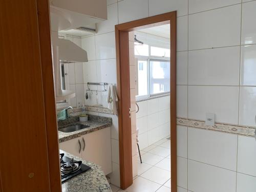 a small kitchen with a sink and a mirror at Apartamento junto mar, bem ventilado e iluminado - Antilhas 679 in Capão da Canoa