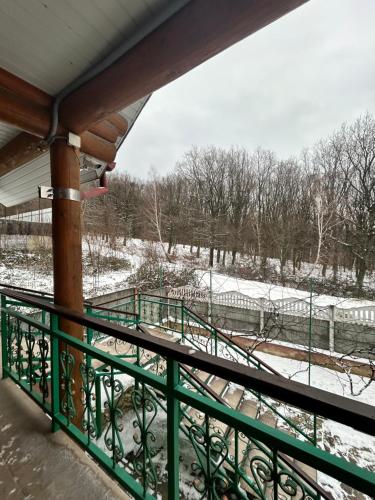 a porch with a green railing and a snow covered field at Заміський будинок кімната студія Pet - friendly in Mukacheve