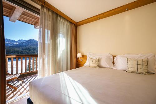 una habitación con una cama grande y un balcón en Maribel Hotel, en Madonna di Campiglio