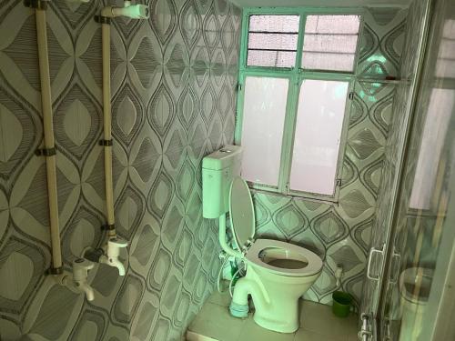 a bathroom with a toilet and a window at Krishna guest house in Sāmbhar