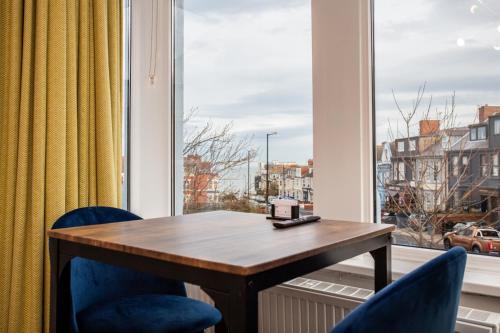 a desk and two chairs in front of a window at Staycoastal Linden Hotel Family Deluxe Suite in Whitley Bay