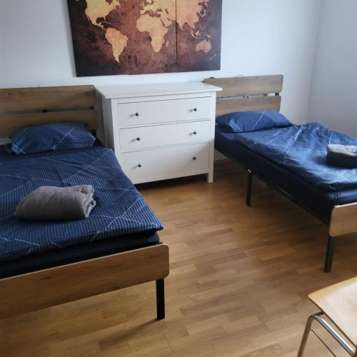 zwei Betten mit blauen Kissen in einem Zimmer mit Kommode in der Unterkunft Bel - Self Check-Inn in Eggenfelden