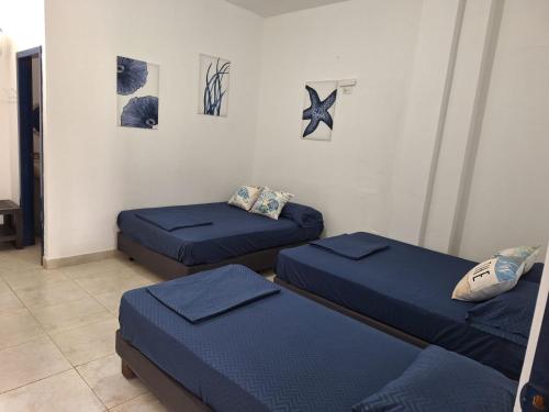 three beds in a room with blue sheets at Sol de Ayangue in Ayangue