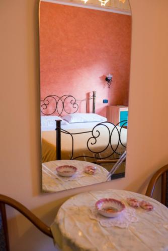 a mirror reflecting a bedroom with a bed and a table at Hotel Nizza in Nizza di Sicilia