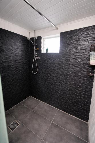 a bathroom with a black brick wall and a shower at KaZen chez Steph in Petite Île