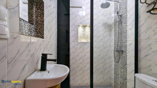 a white bathroom with a sink and a shower at Chic studio with parking & balcony in Yaoundé