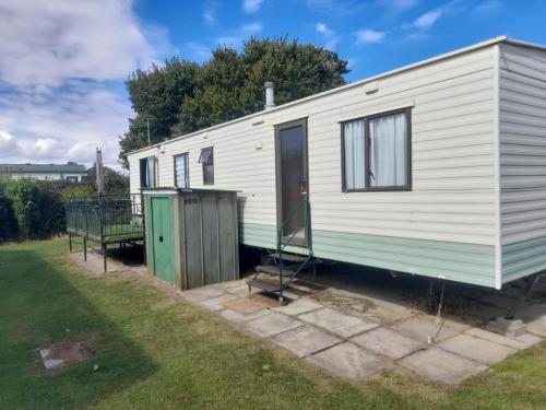 a white caravan with a green door on a yard at T & L CARAVANs in Skegness