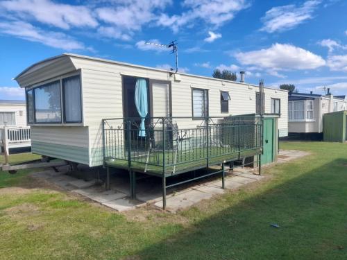 a mobile home with a deck on a lawn at T & L CARAVANs in Skegness