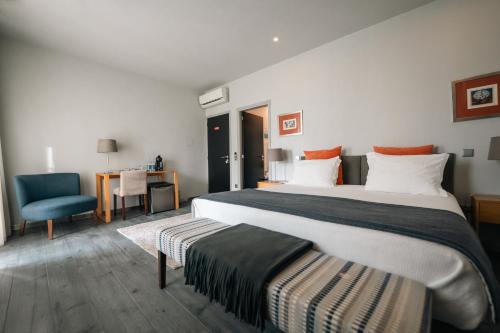 a hotel room with two beds and a chair at Santo Thyrso Villas in Santo Tirso